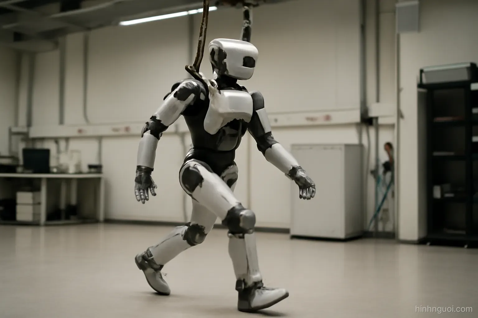 Robot hình người đang bước đi với đầu gối hơi co trên sàn phòng lab